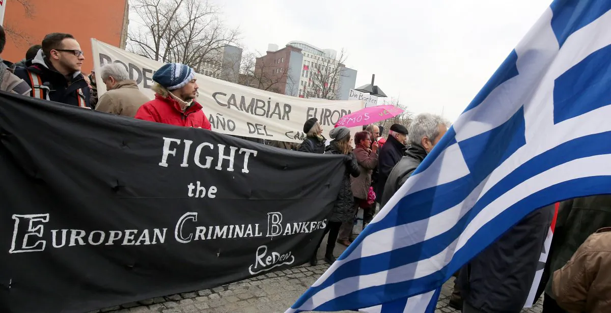 Protesters hold a sign reading “Fight the European Criminal Bankers” and a Greek flag in front of the German FINANCE Ministry in Berlin on March 14, 2015. (Wolfgang Kumm/AFP/Getty Images)