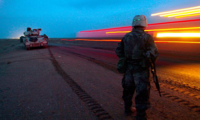 A soldier from the U.S. Army A Company 3rd Battalion 7th Infantry Regiment watches the blur of a convoy of 3rd Infantry Division forces as it passes by, pushing deeper into Iraq from the south Saturday, March 22, 2003. (AP Photo/John Moore)