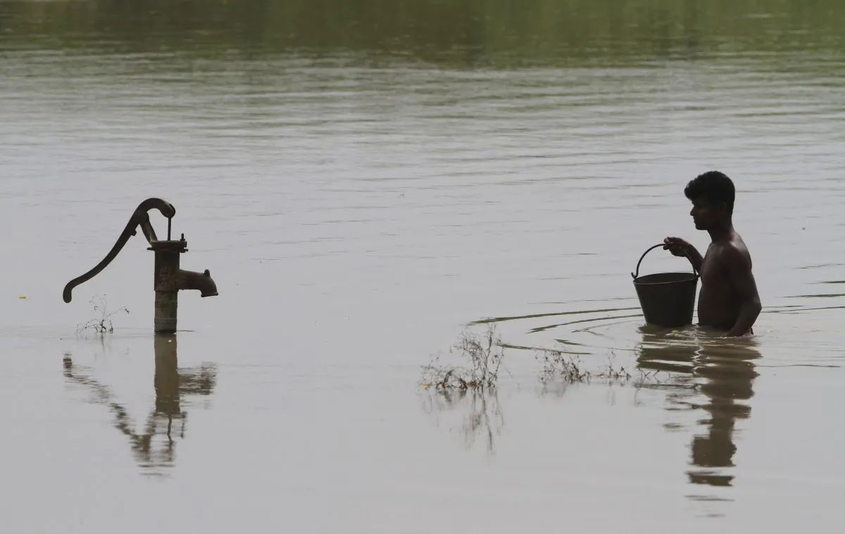An Indian villager walks through floodwaters to collect drinking water from a hand pump in Burhaburhi village in the Morigaon district of north eastern Assam state, India. A UN report released, March, 20, 2015, warns that the world will suffer a serious shortfall of potable water by 2030 unless people and nations dramatically change the way they use the resource. (AP/Anupam Nath)