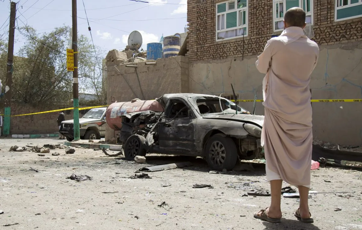 A man looks at a damaged car after a suicide attack in Sanaa, Yemen, Friday, March 20, 2015. (AP Photo/Hani Mohammed)