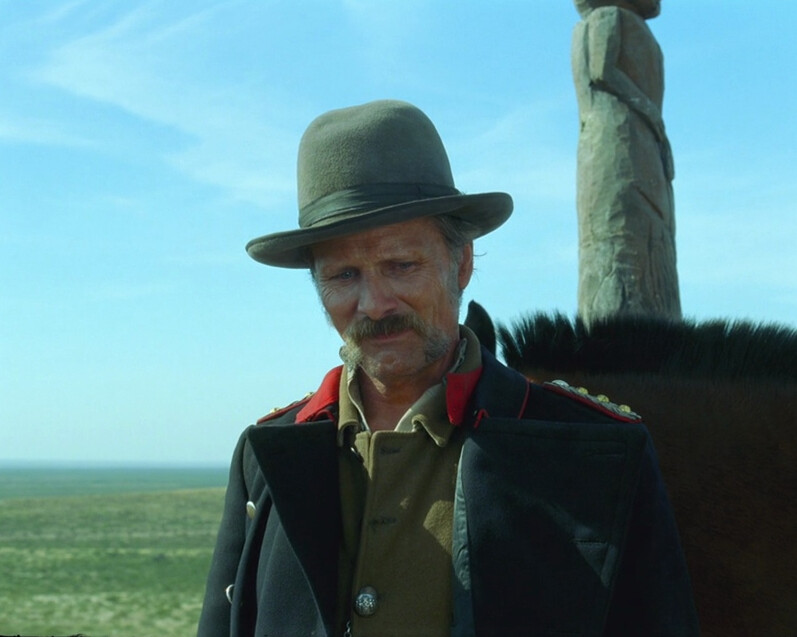 man looking at the grass around his feet in "Jauja"