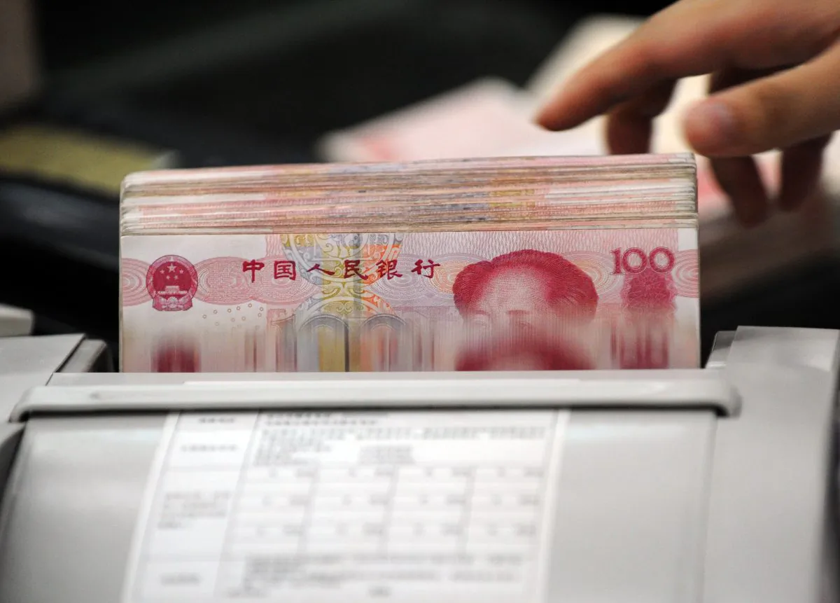 A Chinese bank clerk uses a machine to count the stacks of 100 yuan notes for a customer at a bank in Hefei, Anhui Province, China on Oct. 14, 2010. (STR/AFP/Getty Images). 