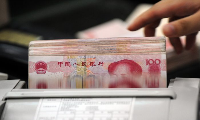 A Chinese bank clerk uses a machine to count the stacks of 100 yuan notes for a customer at a bank in Hefei, Anhui Province, China on Oct. 14, 2010. (STR/AFP/Getty Images). 