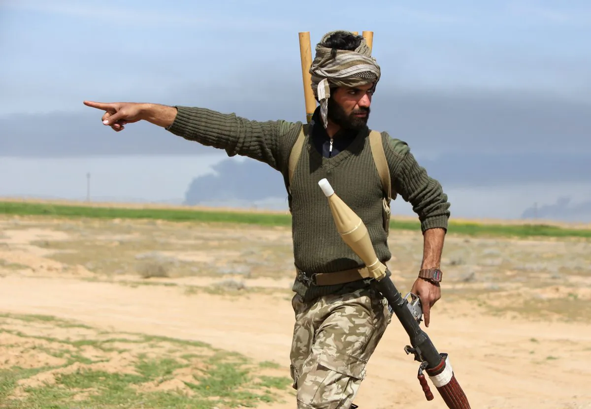 An Iraqi Shiite fighter and member of Iraq's Popular Mobilisation units supporting Iraqi government forces in the battle against the Islamic State (IS) points in the village of Albu Ajil, east of the northern city of Tikrit, on March 8, 2015 during a military operation to regain control of the Tikrit area. Some 30,000 Iraqi security forces members and allied fighters launched an operation to retake Tikrit at the beginning of March, the largest of its kind since Islamic State (IS) group forces overran swathes of territory in June. AFP PHOTO / AHMAD AL-RUBAYE        (Photo credit should read AHMAD AL-RUBAYE/AFP/Getty Images)