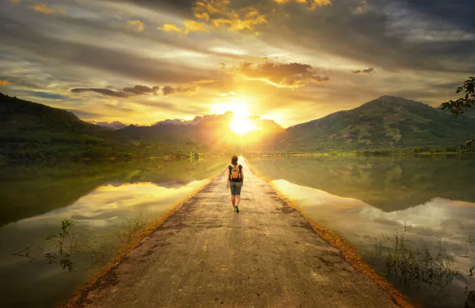 Traveler walking along the road to the mountains via Shutterstock*