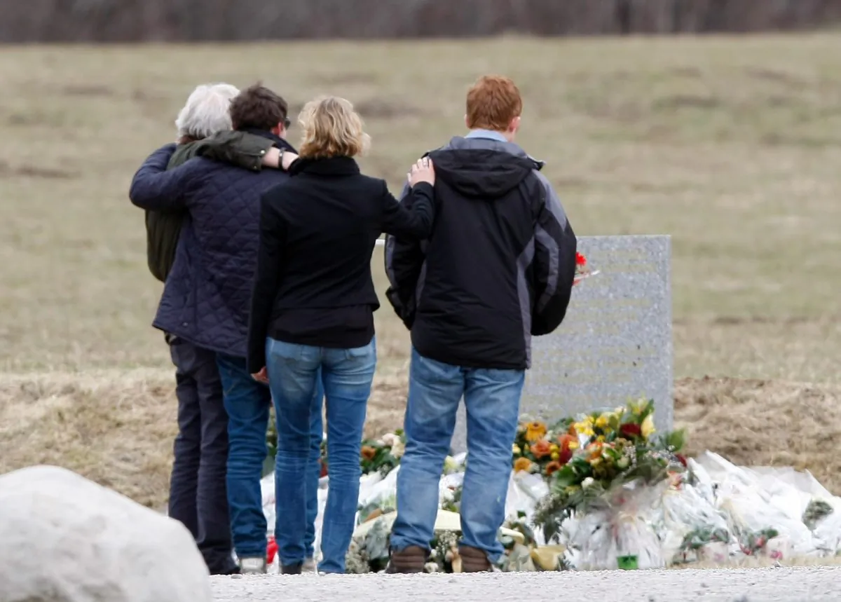 Family members of a victim pause in front of a stele, a stone slab erected as a monument, set up in the area where a Germanwings aircraft crashed in the French Alps, in Le Vernet, France, March 28, 2015. (AP Photo/Claude Paris)