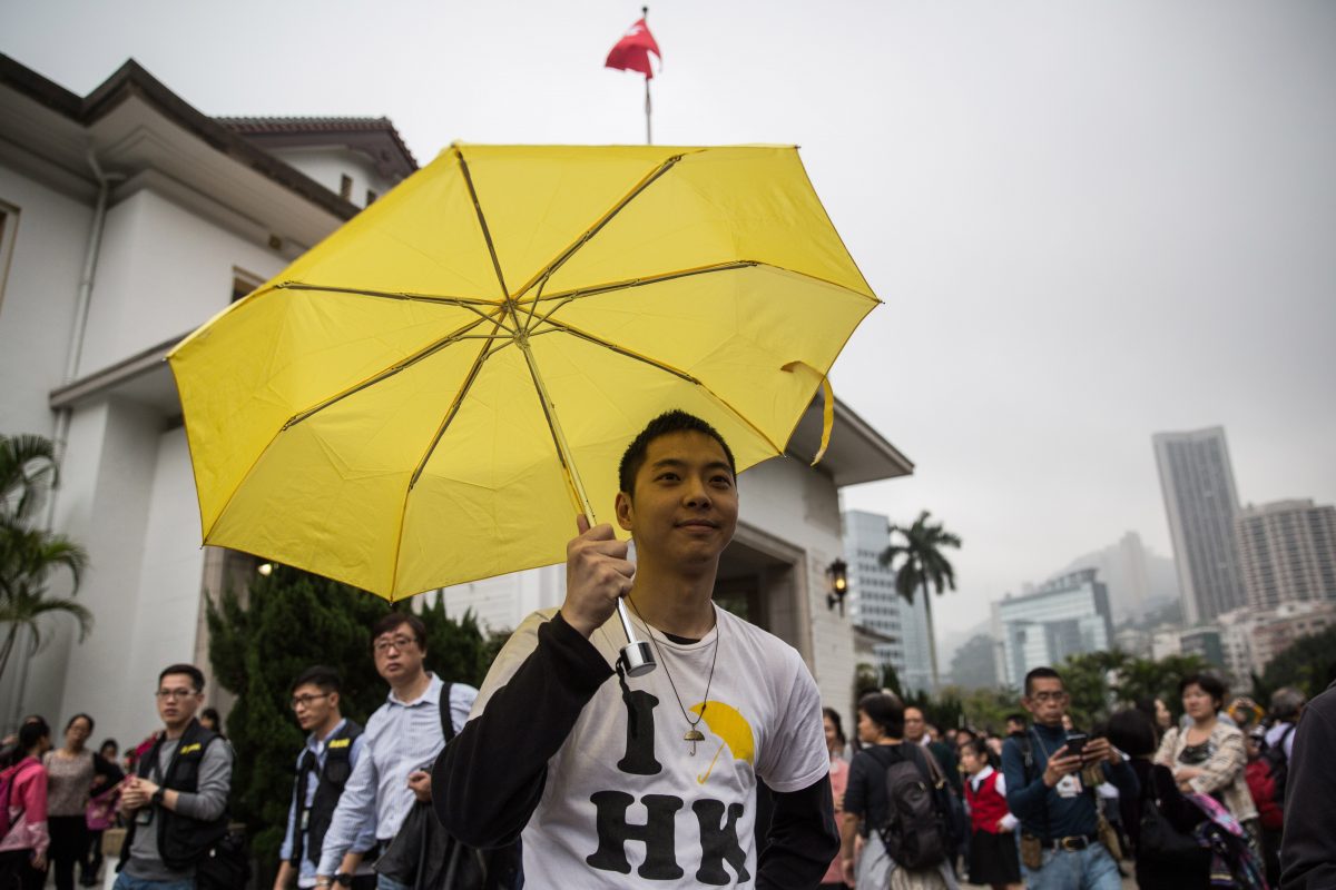 A pro democracy protester raises his yellow umbrella, a symbol for the Umbrella Movement, at the annual open day for the Government House in Hong Kong on March 15, 2015. The annual open day for the Government House saw several small groups of pro-democracy and umbrella movement protesters being swiftly removed from the property grounds by police before an appearance by Hong Kong Chief Executive Leung Chun-ying. AFP PHOTO / ANTHONY WALLACE (Photo credit should read ANTHONY WALLACE/AFP/Getty Images)