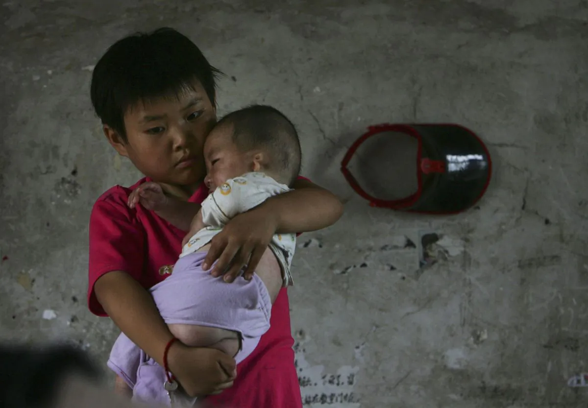 Wang Huaixue holds a baby at Wang Jiayu Orphanage in Anhui Province, China, on July 9, 2006. (China Photos/Getty Images)