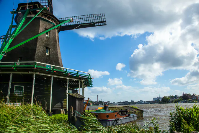 Windmill on a river with a boat, The Netherlands via Shutterstock*
