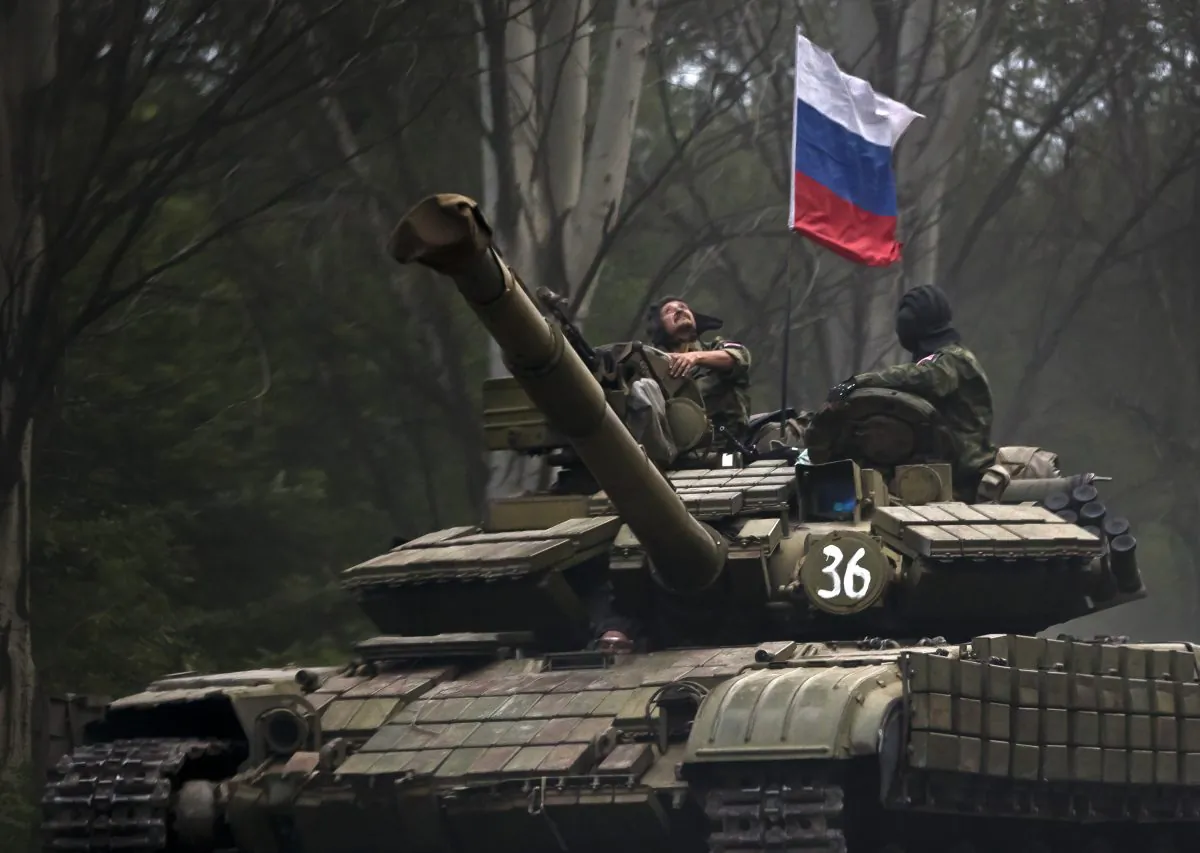a pro-Russian rebel looks up while riding on a tank flying Russia's flag, on a road east of Donetsk, eastern Ukraine on July 29, 2015. (AP Photo/Vadim Ghirda)