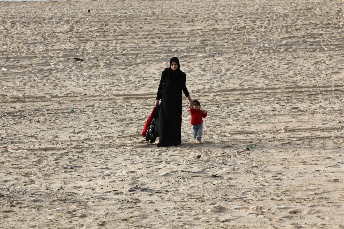 A Palestinian woman walks with her child on the beach on the Mediterranean Sea in Gaza City, Thursday, Oct. 31, 2013. (AP Photo/Adel Hana)