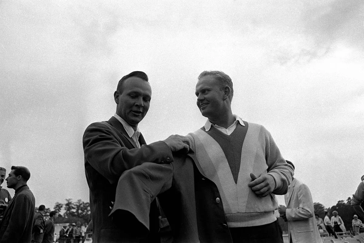 Arnold Palmer (L) helps Jack Nicklaus into the traditional green jacket after Nicklaus' nine-stroke victory at Augusta National Golf Club, April 11, 1965. (AP Photo) 