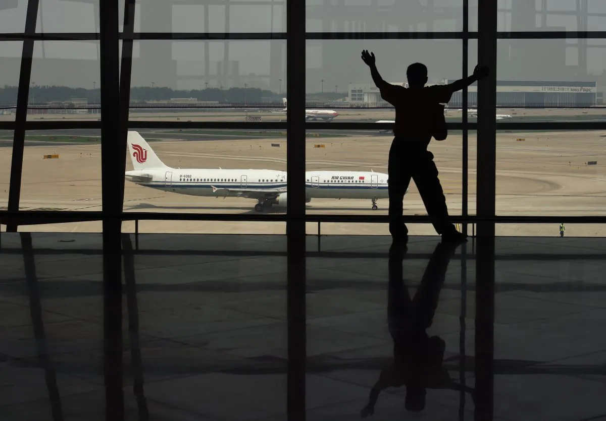 A man looks out at a plane through a window at Beijing international airport. (Greg Baker/AFP/Getty Images)