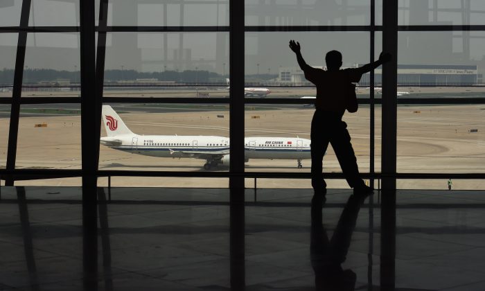 A man looks out at a plane through a window at Beijing international airport. (Greg Baker/AFP/Getty Images)