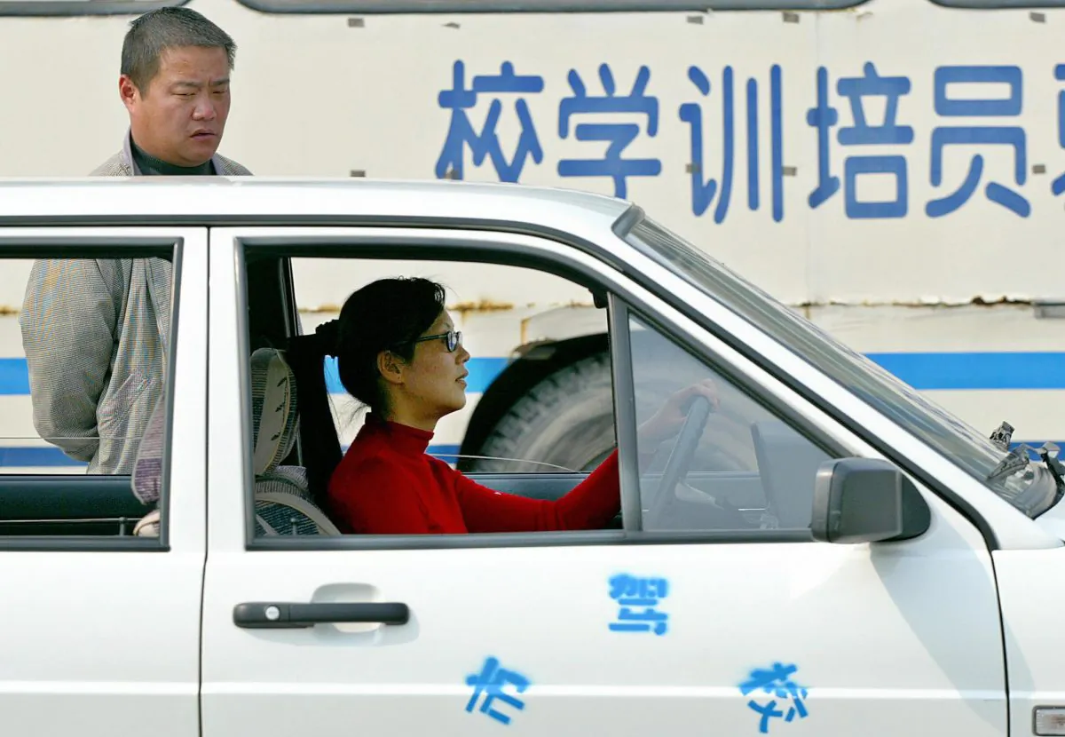 A female trainee (R) studies driving as a teacher watches her at a driving school in Shanghai, 06 April 2004. Bribing driving examiners has become an “unspoken rule” in China to pass the driving tests and get a driver’s license. (Liu Jin/AFP/Getty Images)