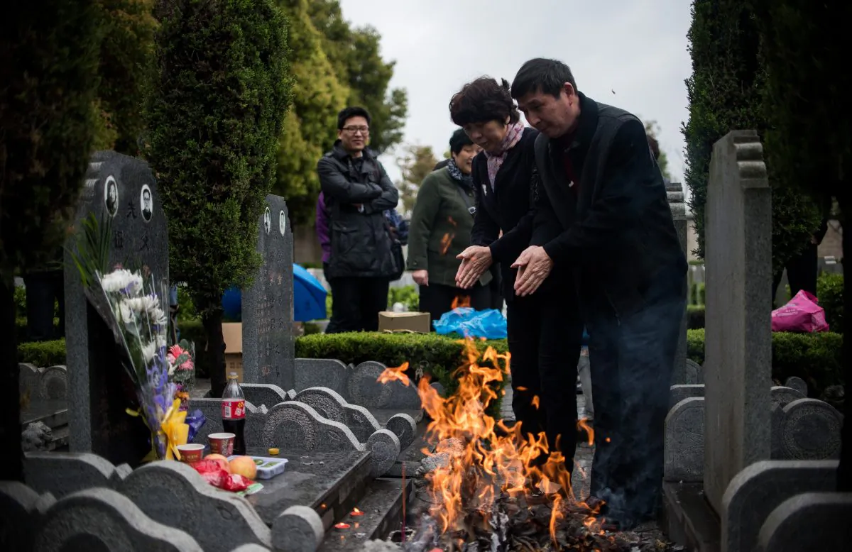 Photo Caption: A couple prays as they burn paper money during the annual 'Qingming' festival, or Tomb Sweeping Day, at a public cemetery in Shanghai on April 6, 2015. (Johannes Eisele/AFP/Getty Images)