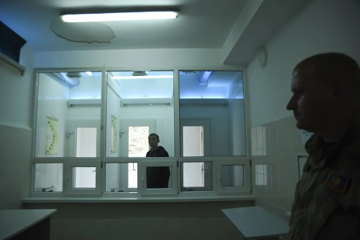 In this photo taken on Thursday, March 26, 2015 Zhdanivka prison guard guards the prisoner, background, who waits for the tuberculosis test to be taken in the village of Zhdanivka, eastern Ukraine. Medical supplies have been in short supply, threatening the lives of nearly 400 prisoners who need treatment. The principal scourge: Tuberculosis. The disease spreads prodigiously in jails and develops into hard-to-treat forms unless properly addressed. "TB is so common within the penitentiary system that many inmates don’t see it as a deadly disease _ they see catching TB as a normal part of life in prison," Doctors Without Borders said in a recent situation report. "Some even tell us they don’t care if they die or not." (AP Photo/Mstyslav Chernov)