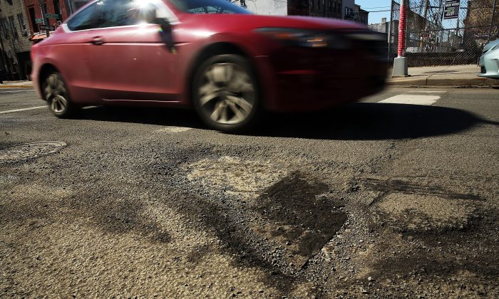 2014 年 2 月 24 日，一辆汽车驶过纽约市布鲁克林区的一个坑洼。  （斯宾塞普拉特/盖蒂图片社）