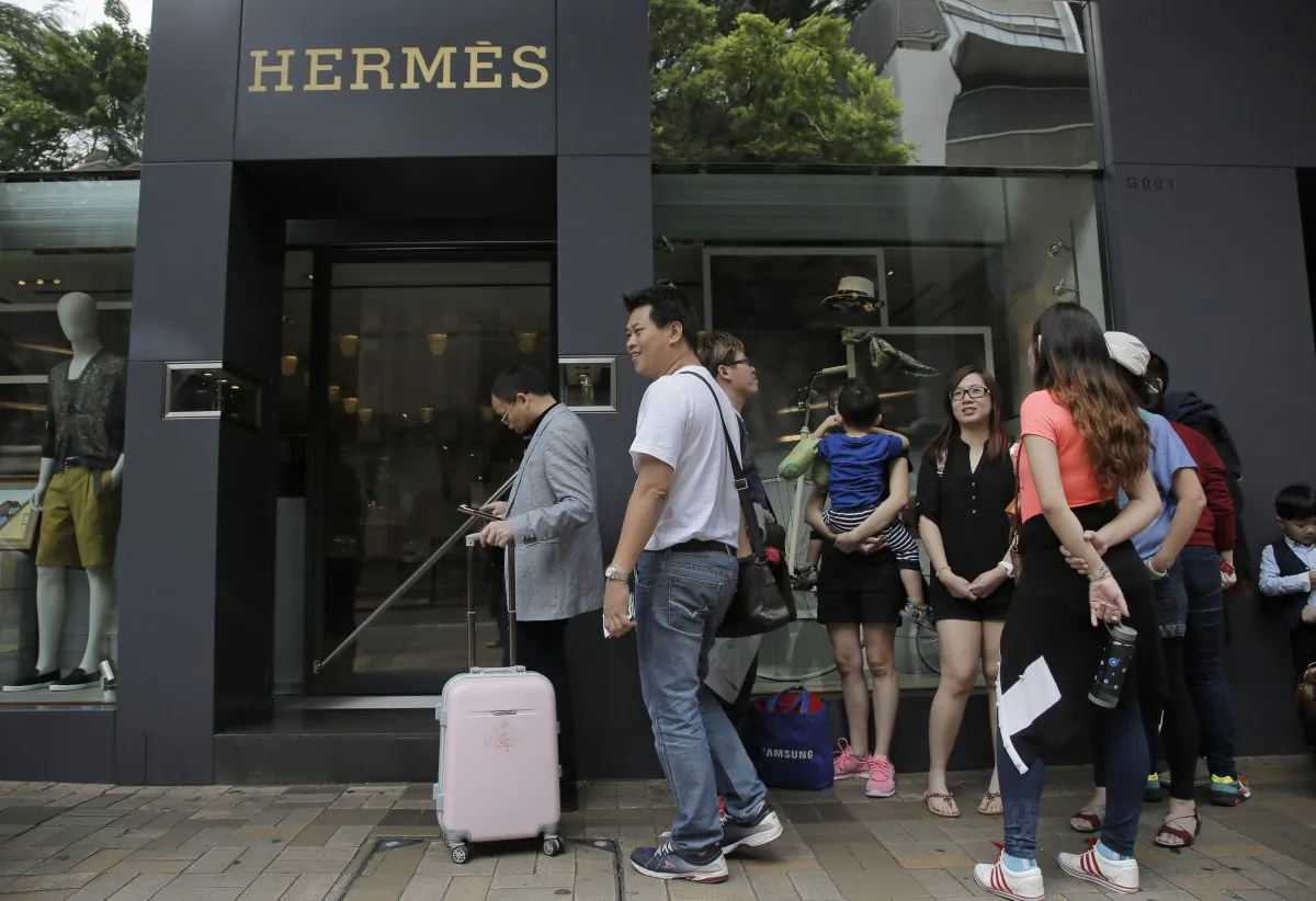 Mainland Chinese tourists queue up outside a luxury brand boutique at a shopping district in Hong Kong, April 12, 2015. (AP Photo/Vincent Yu)