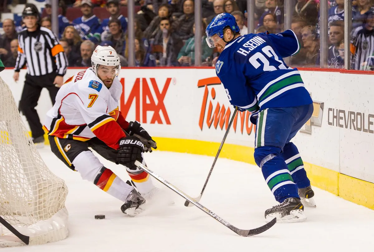 Henrik Sedin of the Vancouver Canucks plays the puck off the back of the net to elude the check of T.J. Brodie of the Calgary Flames on Jan. 10, 2015 at Rogers Arena in Vancouver. The two Canadian division rivals are slated for an interesting battle in the first round of the NHL Playoffs. (Rich Lam/Getty Images)