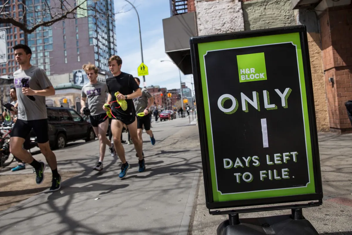 A group of men run past an H&R Block on April 15, 2015 in New York City. Today is the deadline for filing federal income taxes.  (Andrew Burton/Getty Images)