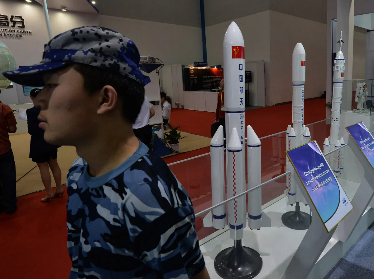 A security guard stands next to models of Chinese rockets on display Beijing on September 24, 2013. The Chinese regime is testing weapons that could soon endanger satellites in all orbits. (Mark Ralston/AFP/Getty Images)