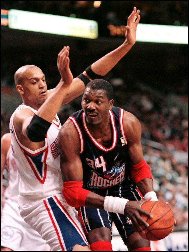 The Houston Rockets' Hakeem Olajuwon (R) drives under and around Philadelphia 76ers Scott Williams during their. Olajuwon's