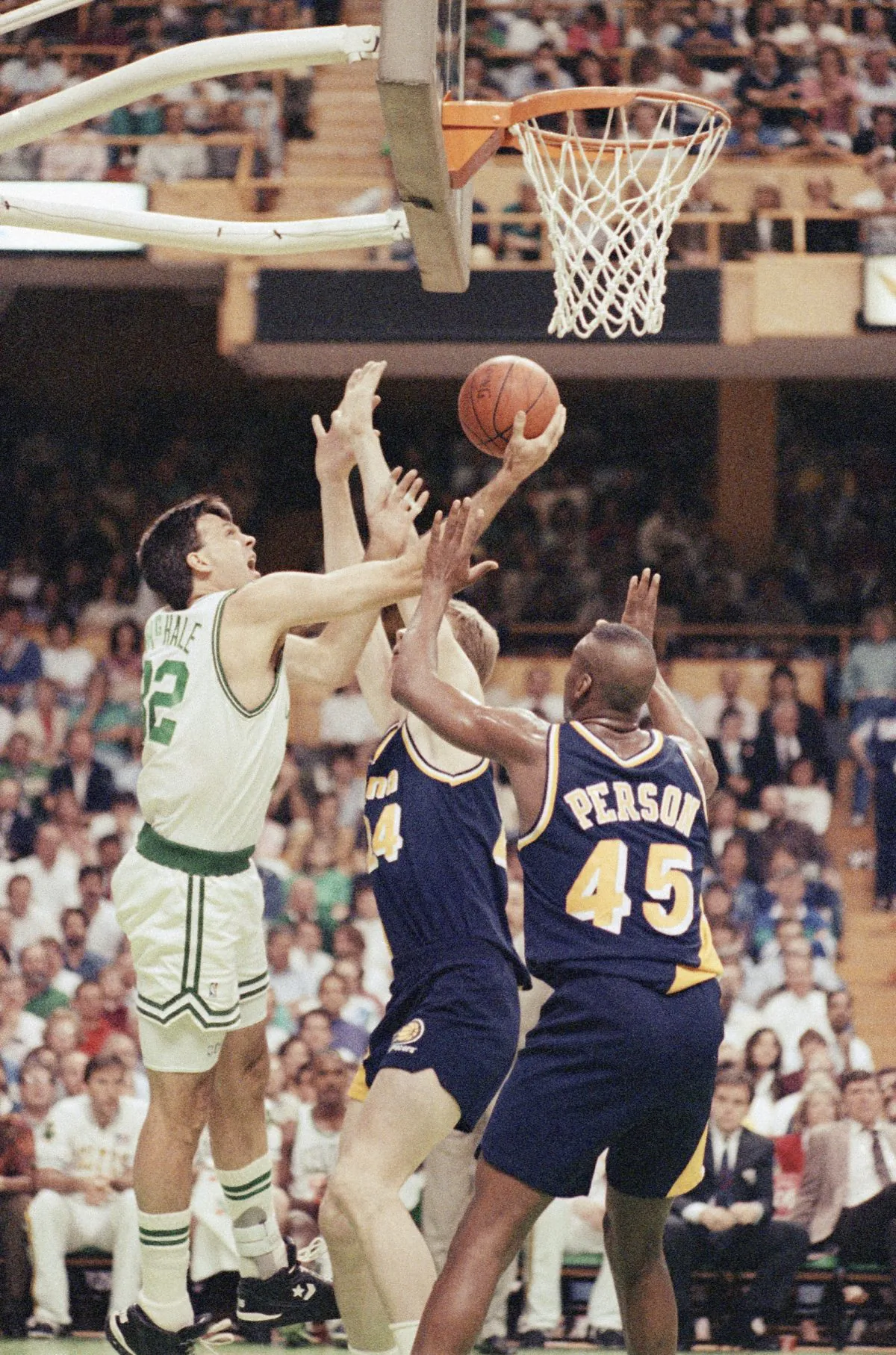 Boston Celtics forward Kevin McHale (L) puts the ball through the out-stretched arms of Indiana Pacers forward Chuck Person (R) and center Rik Smits for the basket during first period action of their NBA playoff contest, Friday night, April 26, 1991 at the Boston Garden in Boston. (AP Photo/Eric Risberg) 
