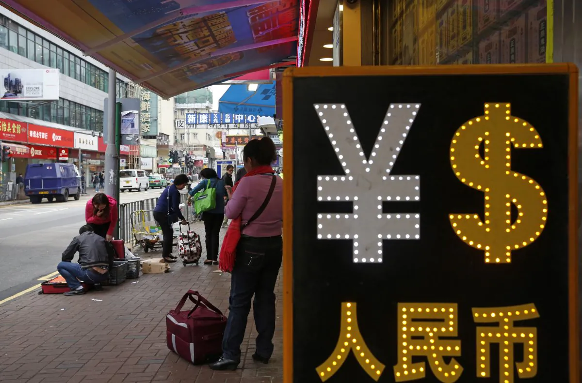 A trader packs goods near a currency exchange shop in Hong Kong, on April 10, 2015. (AP Photo/Kin Cheung)