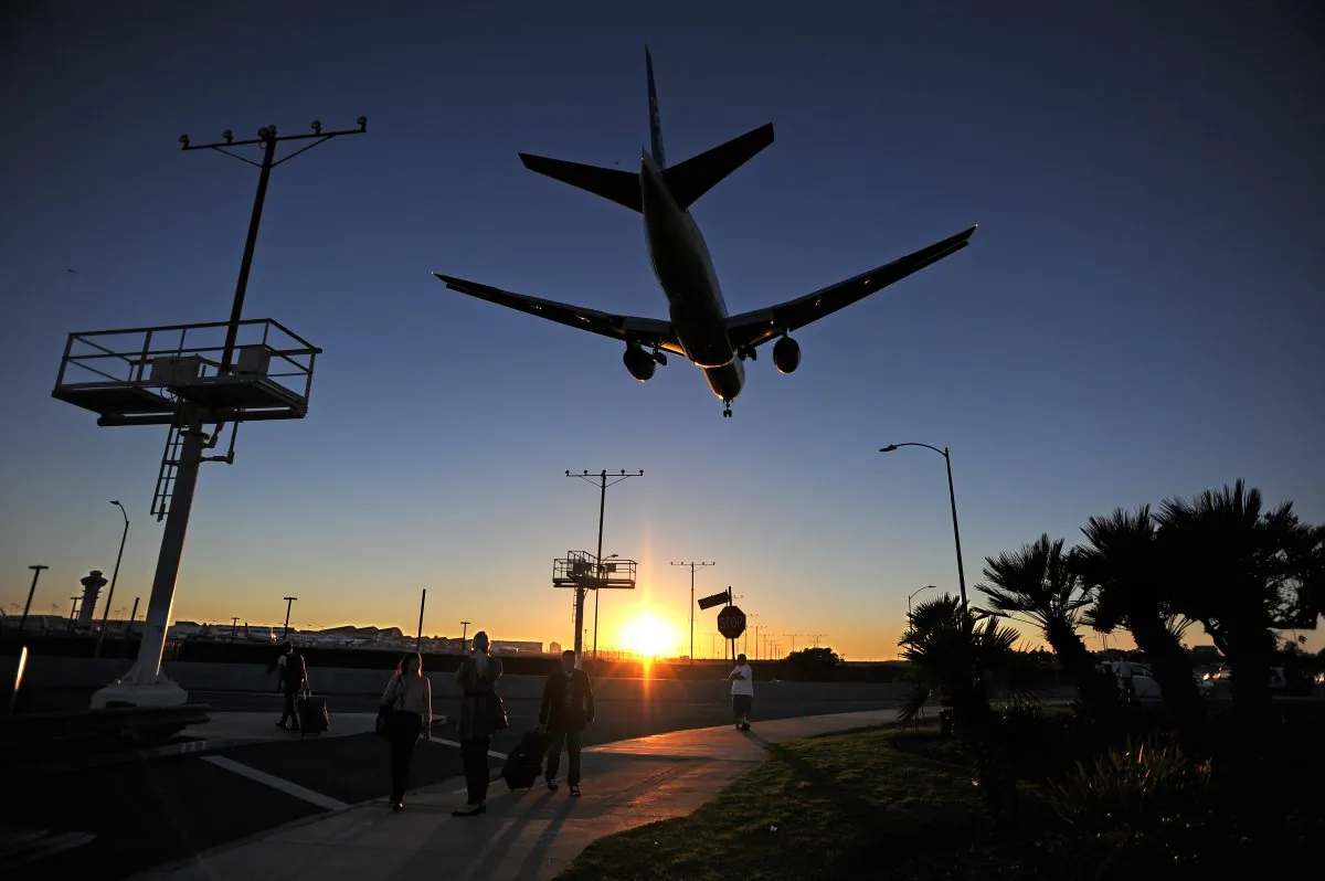 Passengers pull their luggage outside Los Angeles International Airport (LAX) as a plane comes in for a landing at dusk in Los Angeles on Nov. 1, 2013. (Robyn BeckAFP/Getty Images)