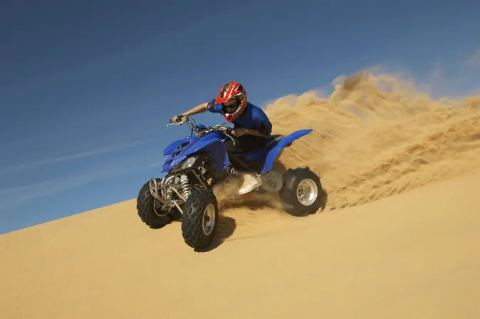 A man riding quad bike in desert via Shutterstock*