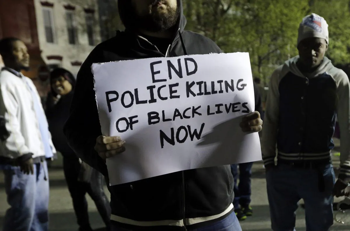 A man holds a sign during a protest for Freddie Gray outside the Baltimore Police Department's Western District police station, Thursday, April 23, 2015, in Baltimore. Gray died from spinal injuries about a week after he was arrested and transported in a police van. (AP Photo/Patrick Semansky)