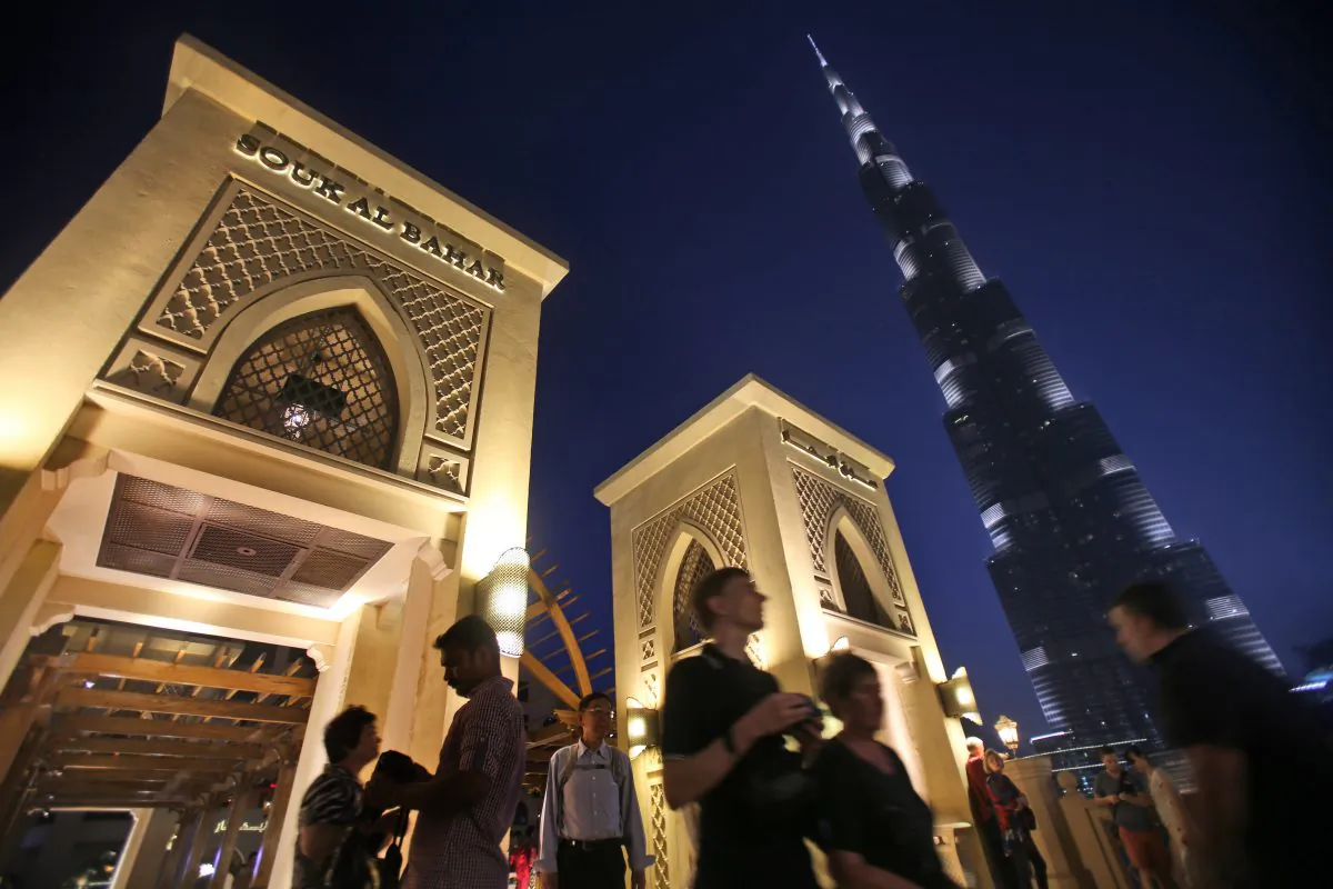With the world tallest tower, Burj Khalifa, in background, tourists and visitors cross a bridge to Souk Al Bahar in Dubai, United Arab Emirates, Monday, April 13, 2015. (AP Photo/Kamran Jebreili)
