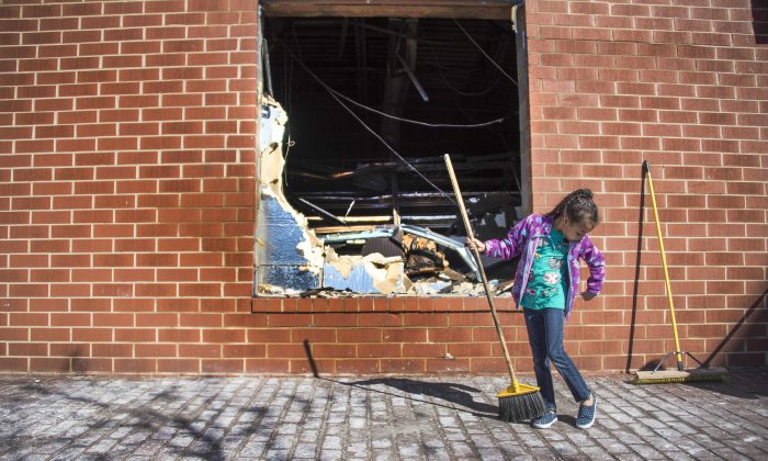 A young girl sweeps up the area outside the CVS Pharmacy in Baltimore that was set on fire during rioting on Monday, on April 28, 2015. (JIM WATSON/AFP/Getty Images)
