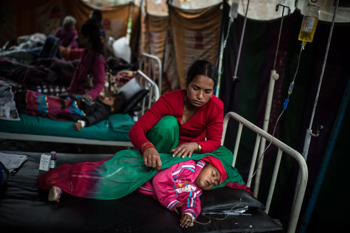 A woman takes care of her daughter as she lies in bed at a temporary hospital suffering from typhoid fever on April 30, 2015, just days after a devastating earthquake struck Nepal near Kathmandu. (David Ramos/Getty Images) 