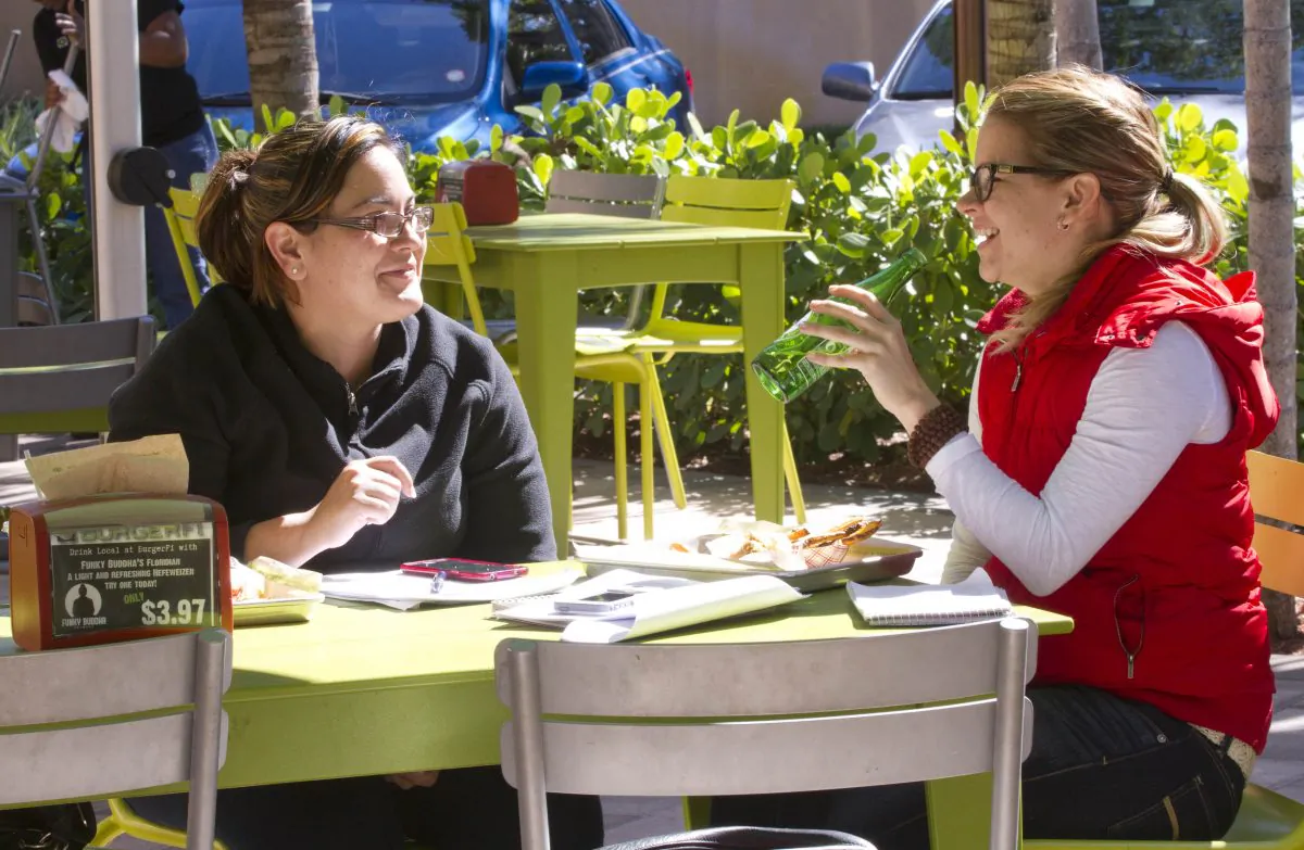 In this Tuesday, Jan. 27, 2015 photo, Sasha Rodriguez, left, and Adriana Olivieri dine on the patio at the BurgerFi restaurant in Aventura, Fla. Companies such as the gourmet hamburger chain BurgerFi plan to nearly double in size from their existing 65 restaurants this year. (AP Photo/Wilfredo Lee)