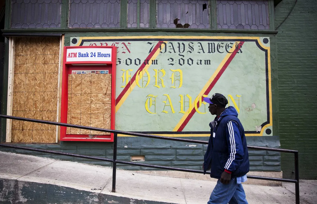 A man walks past the damaged Oxford Tavern in Baltimore. In a presidential campaign where candidates are jockeying to be champions of the middle class and courting donations from the wealthy, the poor are inching their way into the debate. (AP Photo/David Goldman)