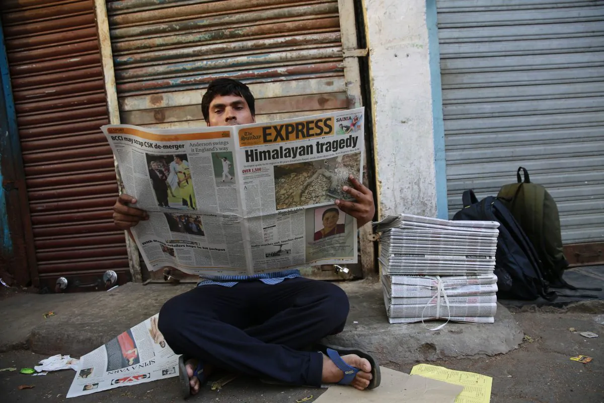 An Indian man reads a newspaper with front-page news of Nepal earthquake in Mumbai, India, on April 26, 2015. (AP Photo/Rafiq Maqbool)