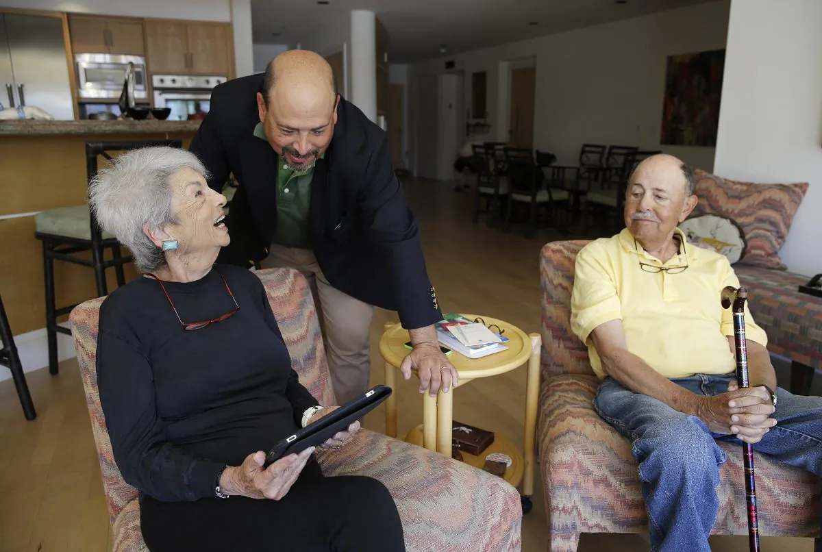 Phil Dworsky visits with his parents, Dorothy and Bill Dworsky, at their home in San Francisco. Each time an elder Dworksy opens the refrigerator, closes the bathroom door or lifts the lid on a pill container, tiny sensors in their home make notes on a digital logbook, which the younger Dworsky monitors daily on his smartphone. (AP/Eric Risberg)