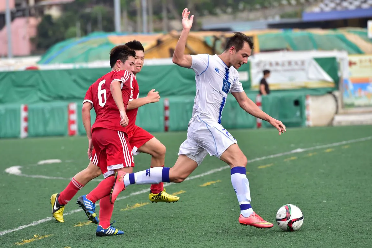 Lucky Mile's Niall Cox (white) attacks the Wanchai defence during their 3-2 win in the HKFA Division 1 match at Happy Valley on Sunday May 3. (Bill Cox/Epoch Times)
