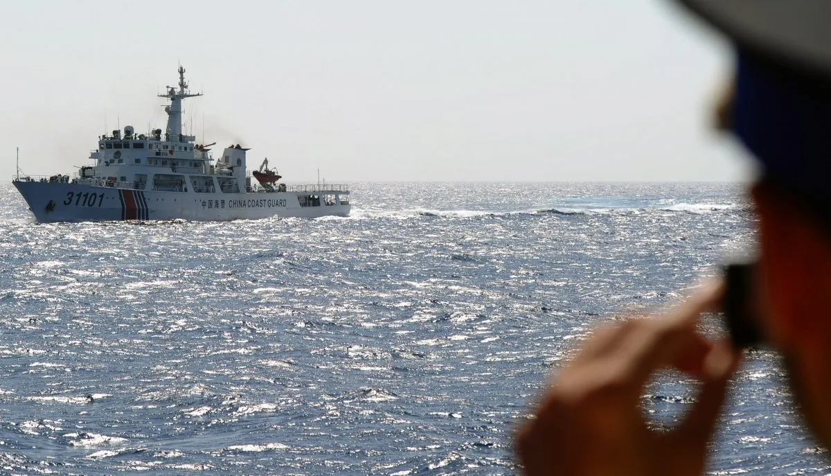 A Vietnamese coast guard officer takes a picture of a China Coast Guard ship in the South China Sea on May 14, 2014, off Vietnam's central coast. The Chinese regime is now defending airspace over the region. (Hoang Dinh Nam/AFP/Getty Images)
