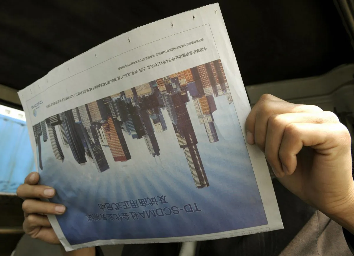 A man reads a newspaper featuring the skyscrapers in Beijing April 24, 2008. (LIU JIN/AFP/Getty Images)