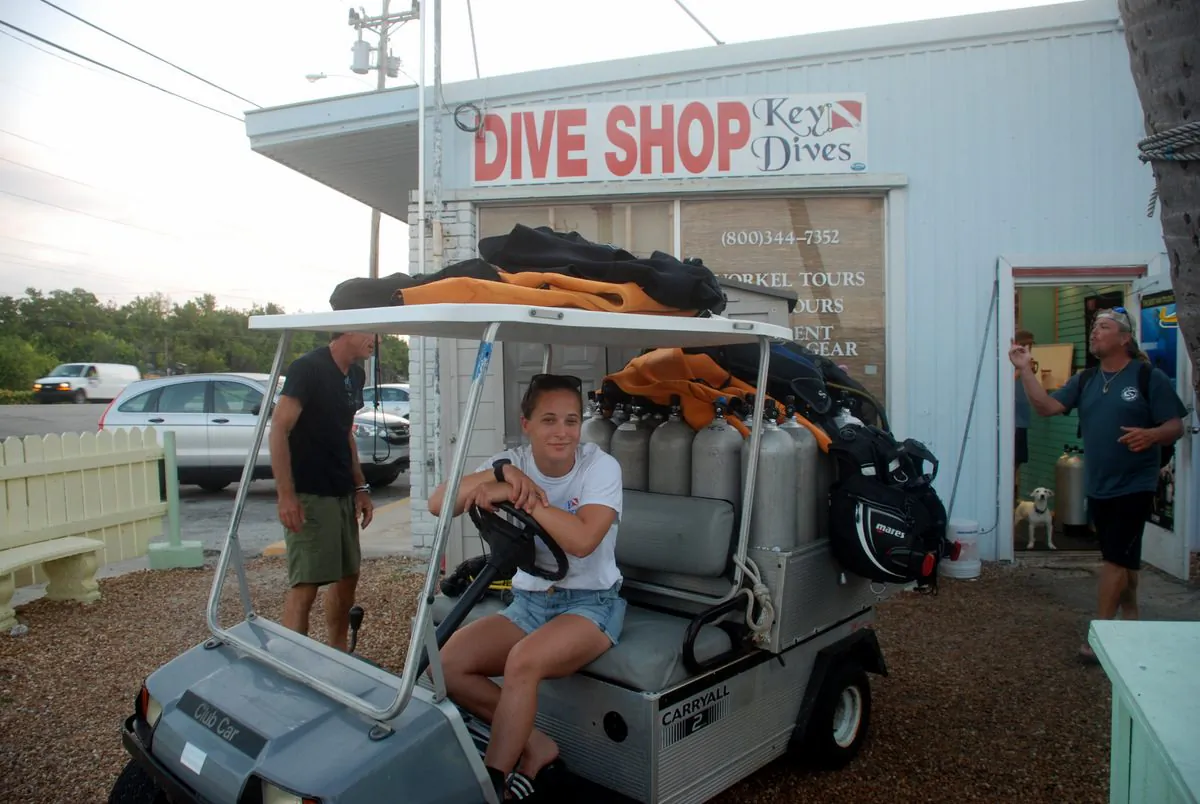 Key Dives divemaster Samantha Schuff with golf cart loaded with divers gear. Key Dives labels and takes gear from the shop to the dive boat and sets it up. (John Christopher Fine copyright 2015)