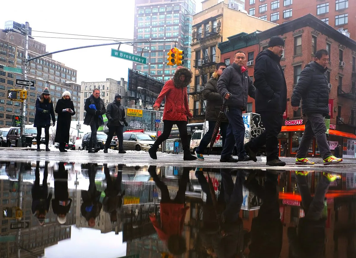 People walk by a puddle made by melted snow on a street in New York,  Feb. 2, 2015. ( Jewel  Samad/AFP/Getty Images)