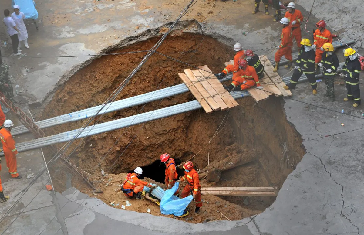 Rescuers move a dead body out of a sinkhole in Shenzhen, China on May 21, 2013. (AFP/AFP/Getty Images)