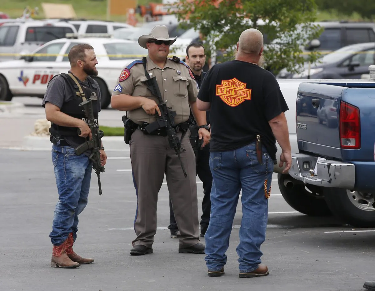 Law enforcement officers talk to a man near the parking lot of a Twin Peaks Restaurant Sunday, May 17, 2015, in Waco, Texas, after a shooting involving rival biker gangs. Waco police Sgt. W. Patrick Swanton told KWTX-TV there were multiple victims after gunfire erupted between the gang members. (Rod Aydelotte/Waco Tribune Herald via AP)