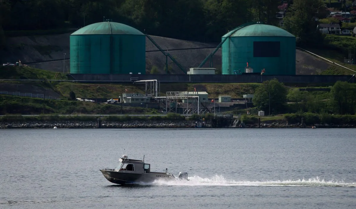 A fishing boat passes the Kinder Morgan Burnaby Terminal in Burnaby, B.C., on May 2, 2014. A prominent economist has dropped out of the National Energy Board’s review of Kinder Morgan's proposed Trans Mountain pipeline expansion, which would nearly triple the capacity of the pipeline that carries crude oil to Vancouver to be loaded on tankers. (The Canadian Press/Darryl Dyck)