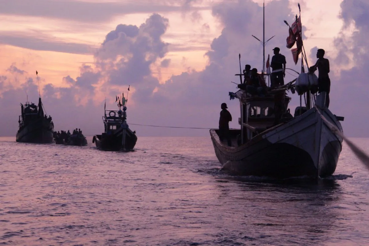 Acehnese fishermen are silhouetted by the rising sun as they rescue migrants who are stranded on their boat on the sea off East Aceh, Indonesia, Wednesday, May 20, 2015. (AP Photo/S. Yulinnas)