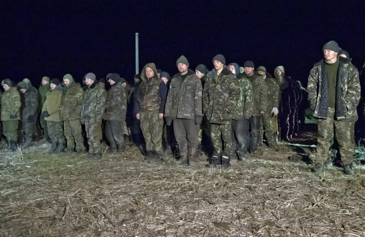 Ukrainian prisoners of war wait in line before a prisoner exchange in Russia-backed separatist controlled territory, near the village of Zholobok, some 20 kilometers (12 miles) west of Luhansk, Ukraine. (AP Photo/Vadim Ghirda)