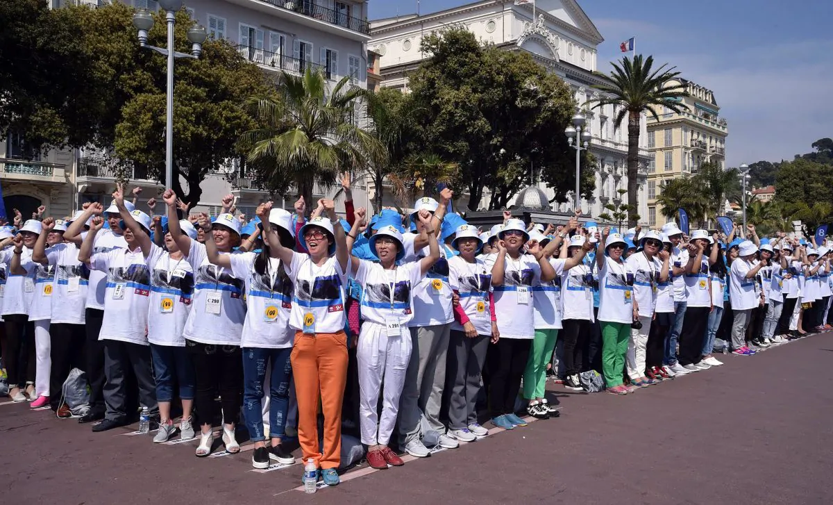 Employees of the Tiens Group at a parade in France on May 8. A number of Chinese firms have rewarded employees with identical package tours. (AP Photo/Lionel Cironneau, File)